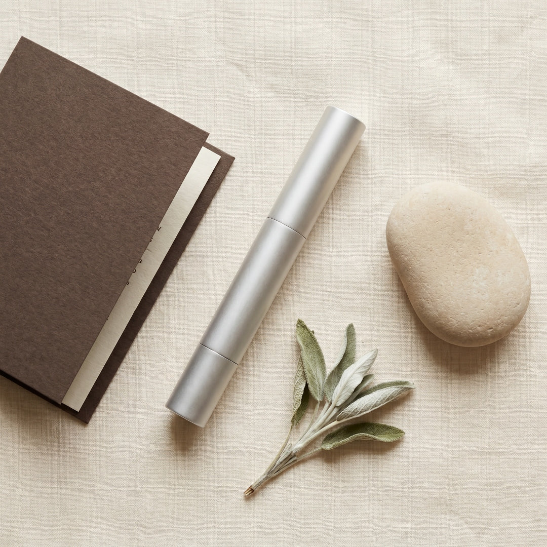 Botanic Cuticle Serum Travel pen flat lay with sage, desert stone, and notebook on cream linen, styled for gifting